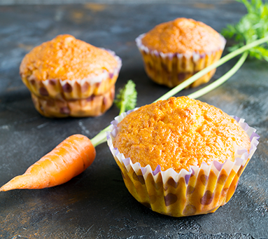 Mini muffins de cenoura dourados em uma mesa clara.